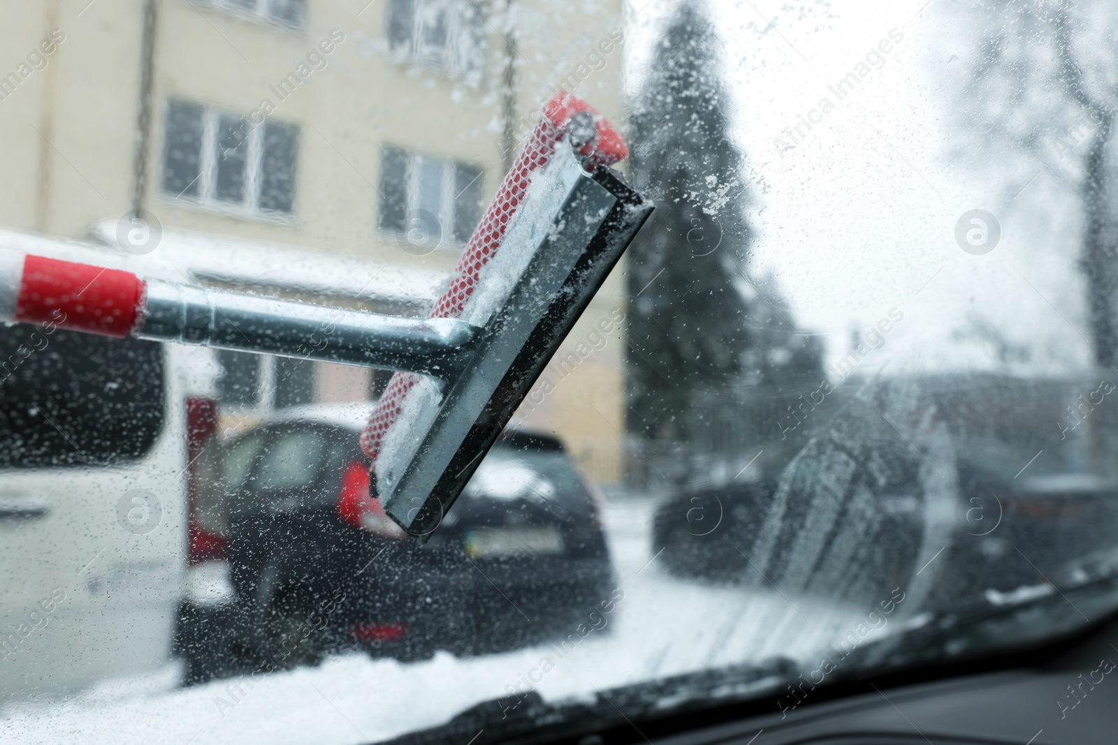 Photo of Cleaning windshield from snow with squeegee, view from inside