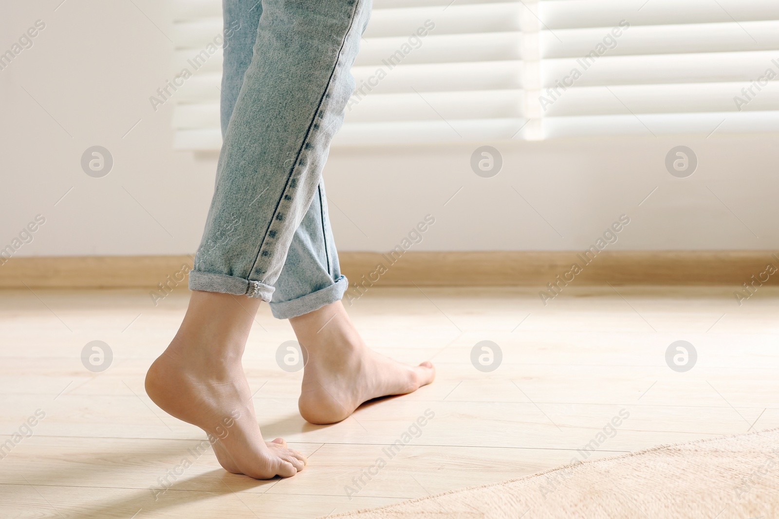 Photo of Woman stepping barefoot in room at home, closeup. Floor heating