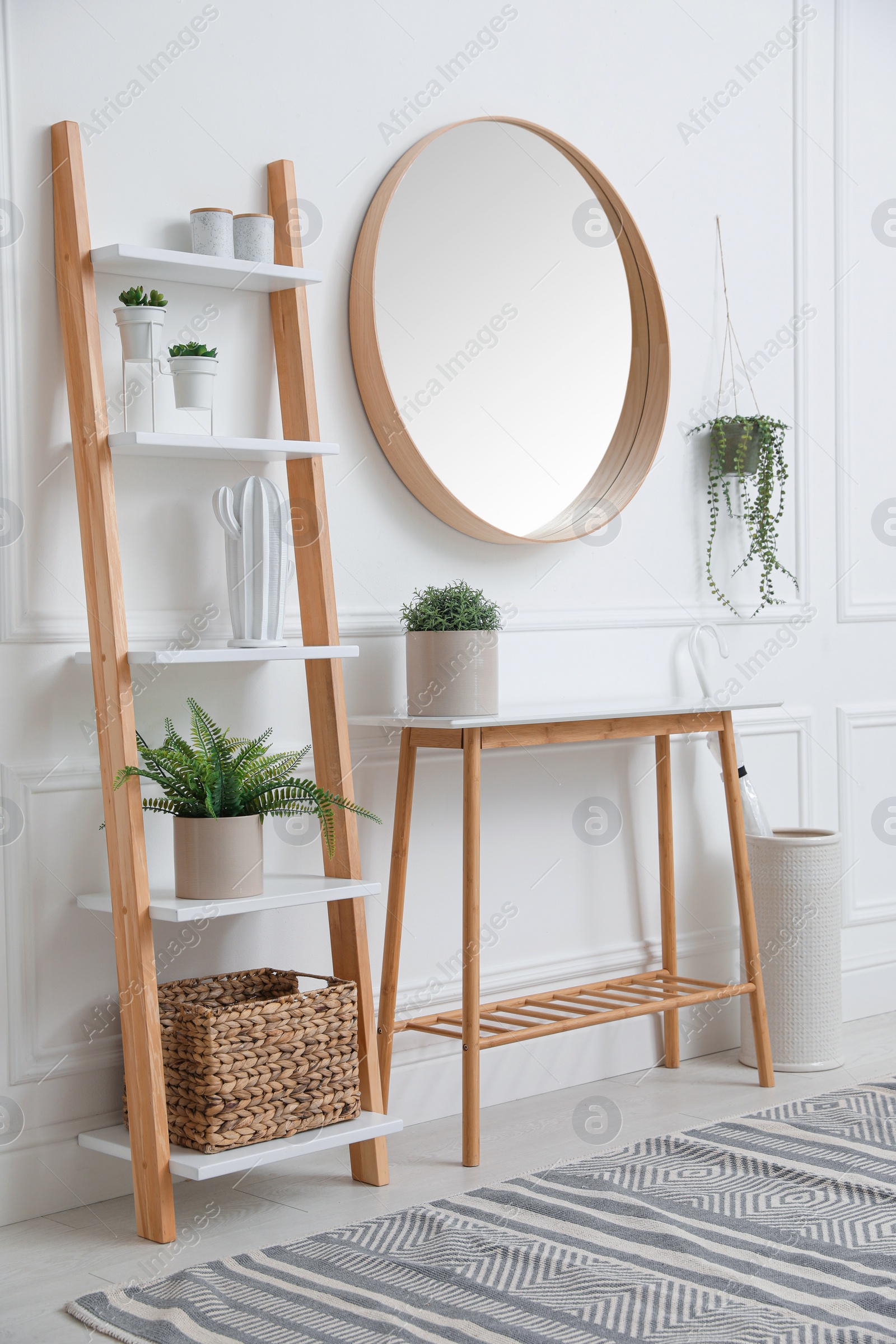 Photo of Console table with shelving unit and mirror on white wall in hallway. Interior design