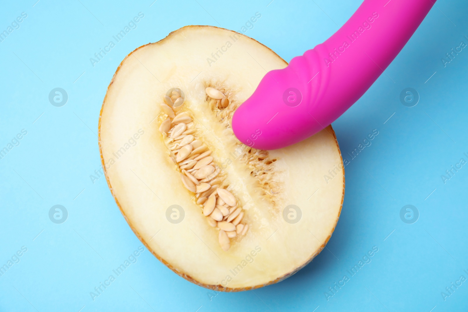 Photo of Half of melon and purple vibrator on blue background, flat lay. Sex concept