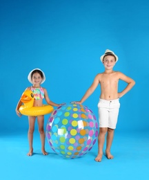 Cute little children in beachwear with inflatable toys on light blue background