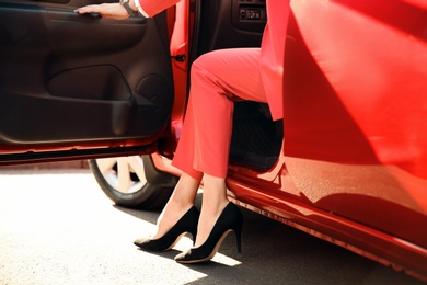 Young businesswoman in stylish suit getting out of car