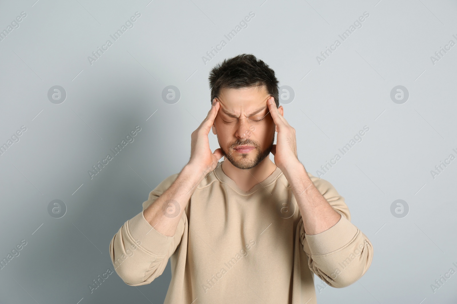 Photo of Man suffering from terrible migraine on light grey background