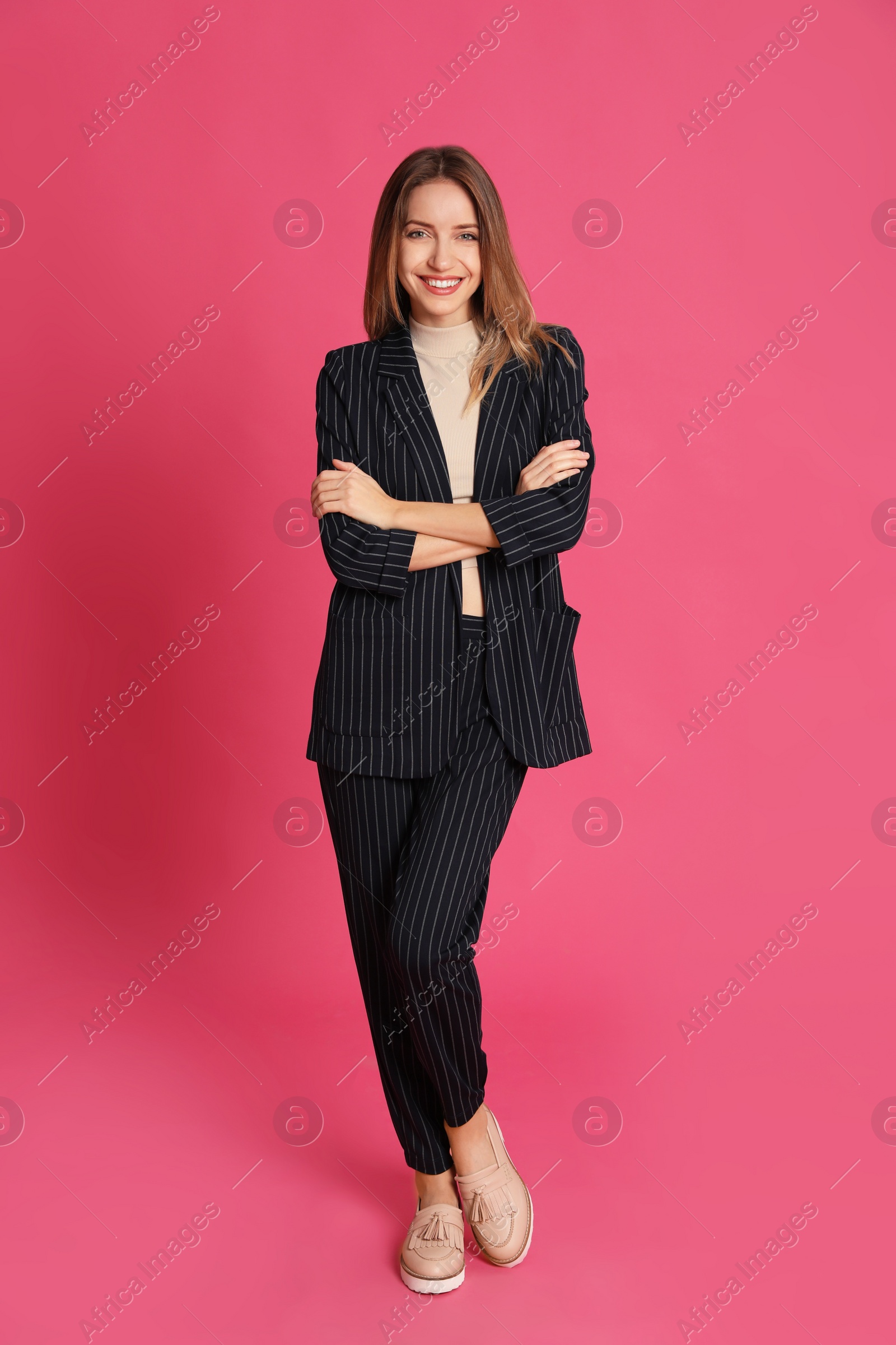 Photo of Full length portrait of beautiful young woman in fashionable suit on pink background. Business attire