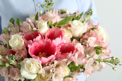 Woman with beautiful bouquet of fresh flowers on light background, closeup