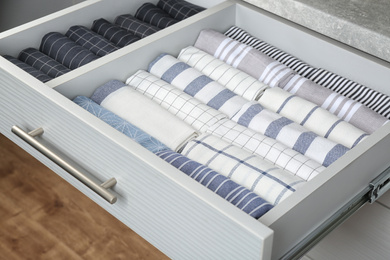 Photo of Open drawer with folded towels. Order in kitchen