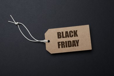 Photo of Tag with words Black Friday on dark background, top view