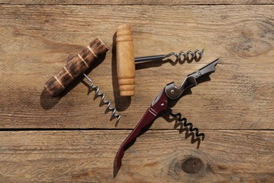 Photo of Different corkscrews on wooden table, flat lay