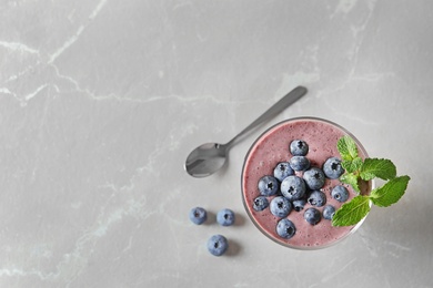 Photo of Glass with blueberry smoothie on light background, top view. Space for text