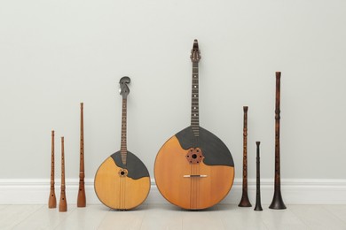 Photo of Set of different wooden musical instruments near white wall indoors