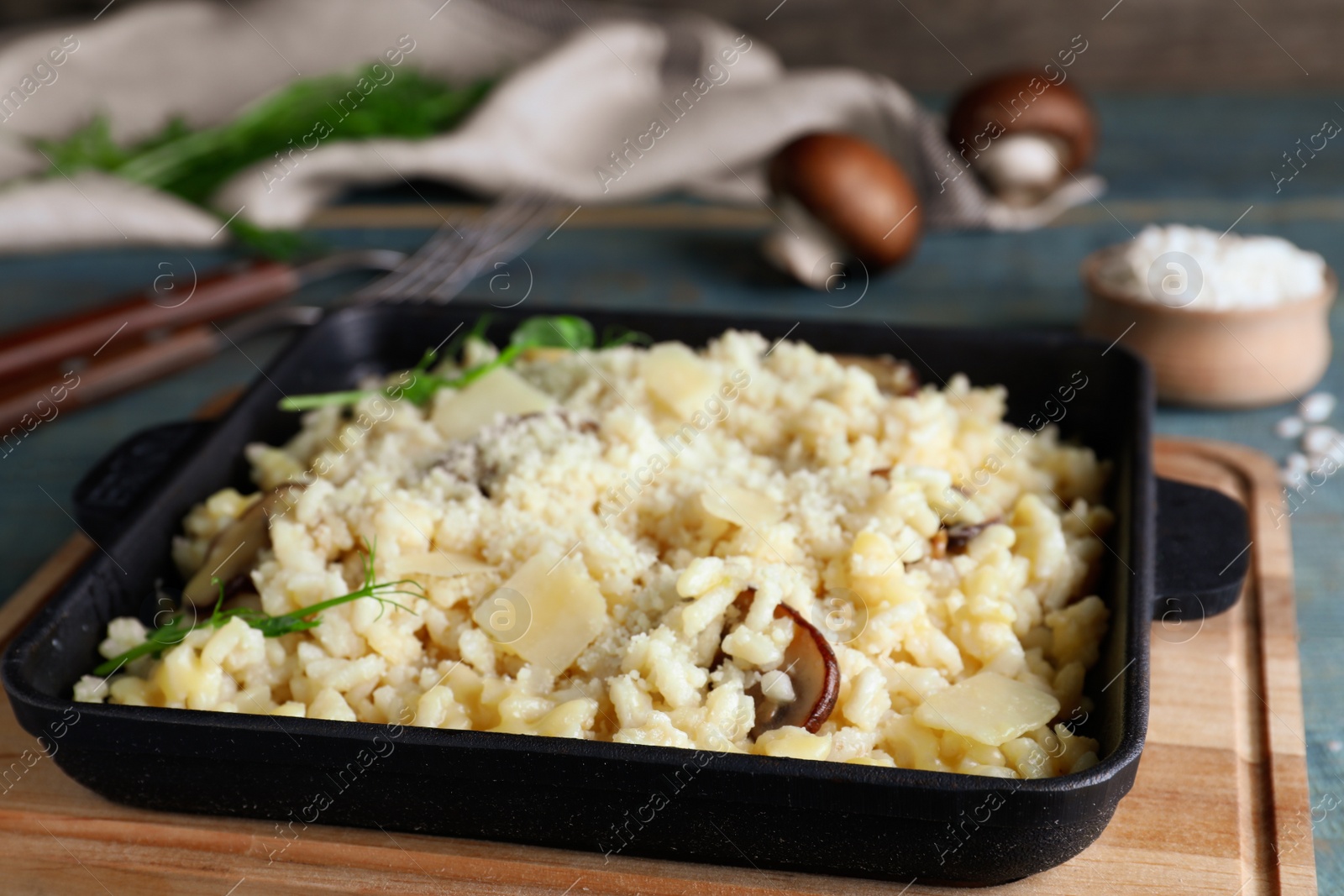 Photo of Delicious risotto with cheese and mushrooms on wooden board, closeup