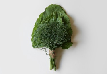 Bunch of dill and beetroot leaves on white wooden table, top view