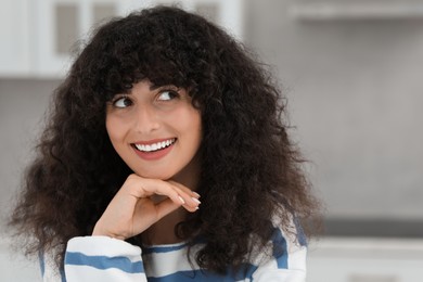 Photo of Portrait of beautiful woman with curly hair on blurred background. Attractive lady smiling and posing for camera