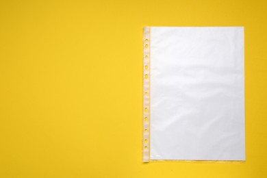 Punched pocket with paper sheet on yellow background, top view. Space for text