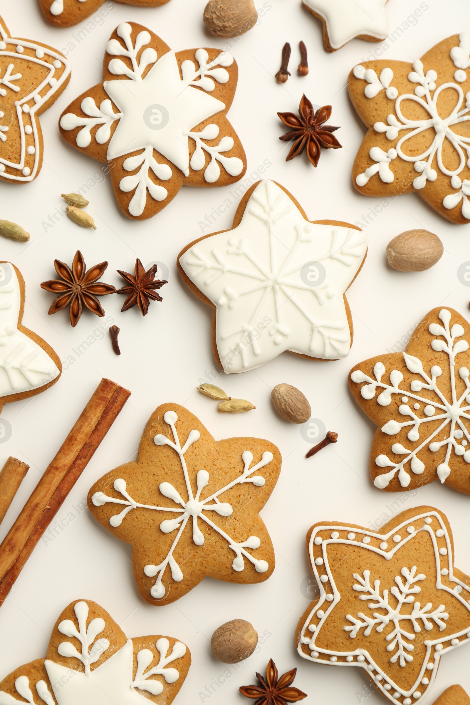 Photo of Tasty Christmas cookies with icing and spices on white background, flat lay