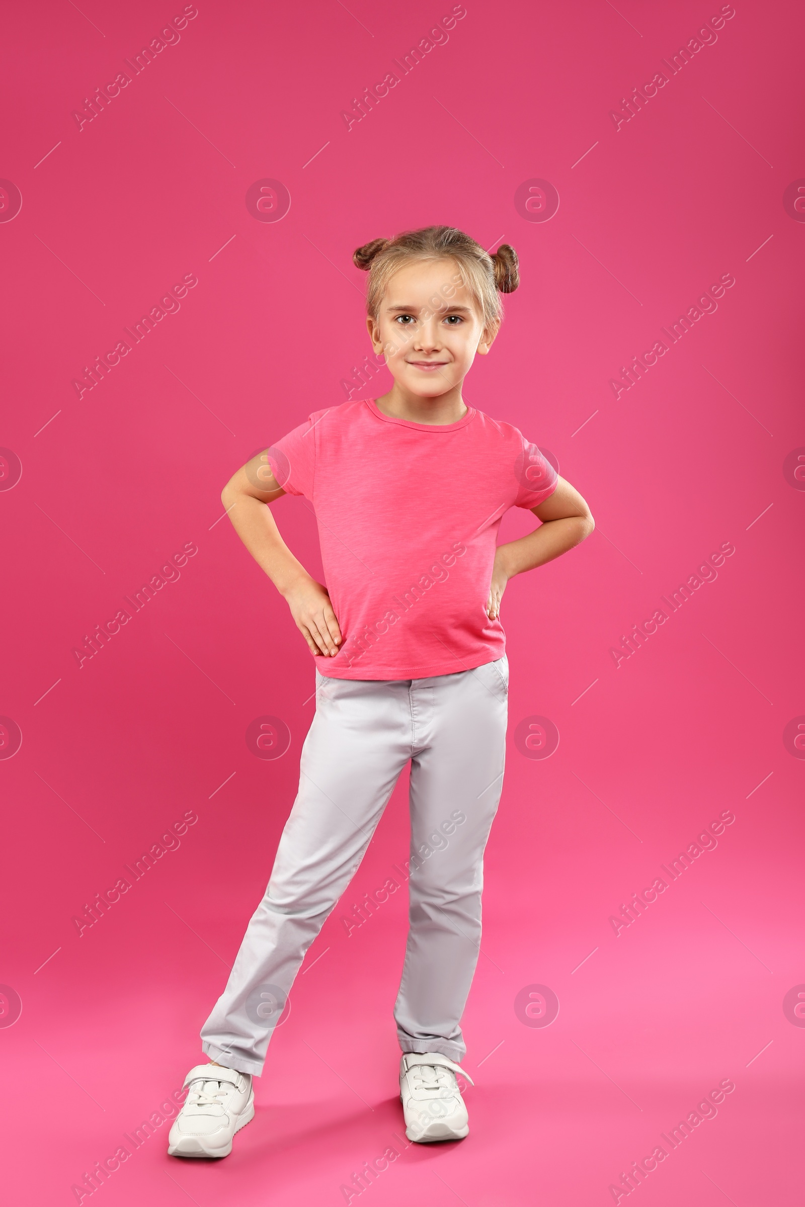 Photo of Cute little girl posing on pink background