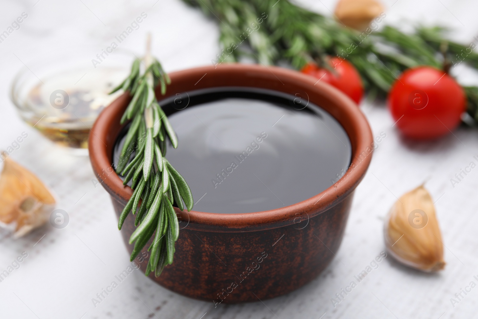 Photo of Organic balsamic vinegar and cooking ingredients on white wooden table, closeup