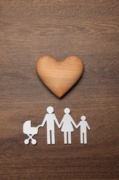 Photo of Paper family cutout and decorative heart on wooden background, flat lay. Insurance concept