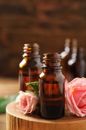 Photo of Bottles of rose essential oil and fresh flowers on table, closeup. Space for text