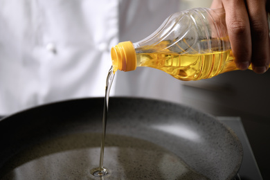 Man pouring cooking oil from bottle into frying pan, closeup