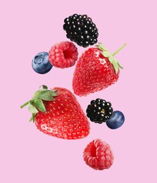 Image of Many different fresh berries falling on pink background