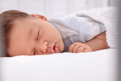 Cute newborn baby sleeping under white plaid on bed, closeup