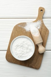 Baking powder in bowl and scoop on white wooden table, top view