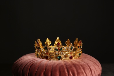 Photo of Beautiful golden crown on pink velvet pillow. Fantasy item