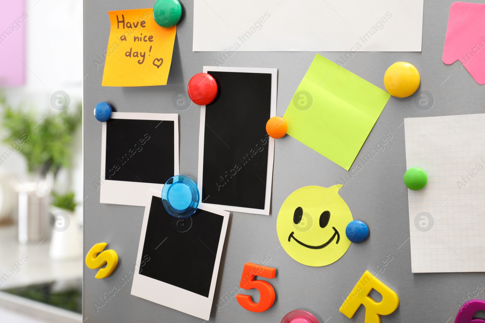 Photo of Sheets of paper and photos with colorful magnets on refrigerator door in kitchen. Space for text