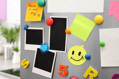 Photo of Sheets of paper and photos with colorful magnets on refrigerator door in kitchen. Space for text