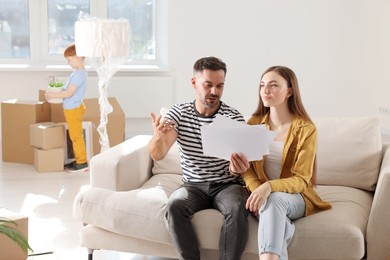 Photo of Family settling into home. Wife with husband choosing interior details while son unpacking boxes in new apartment. Moving day