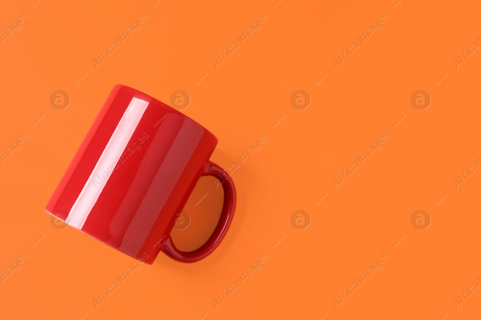 One red ceramic mug on orange background, top view. Space for text Photo of One red ceramic mug on orange background, top view. Space for text