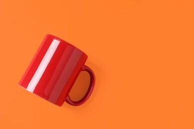 Photo of One red ceramic mug on orange background, top view. Space for text