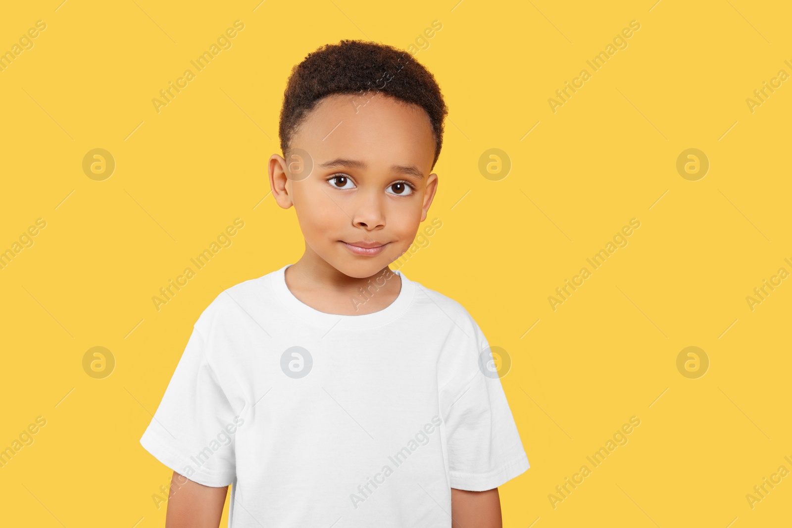 Photo of Portrait of cute African-American boy on yellow background. Space for text