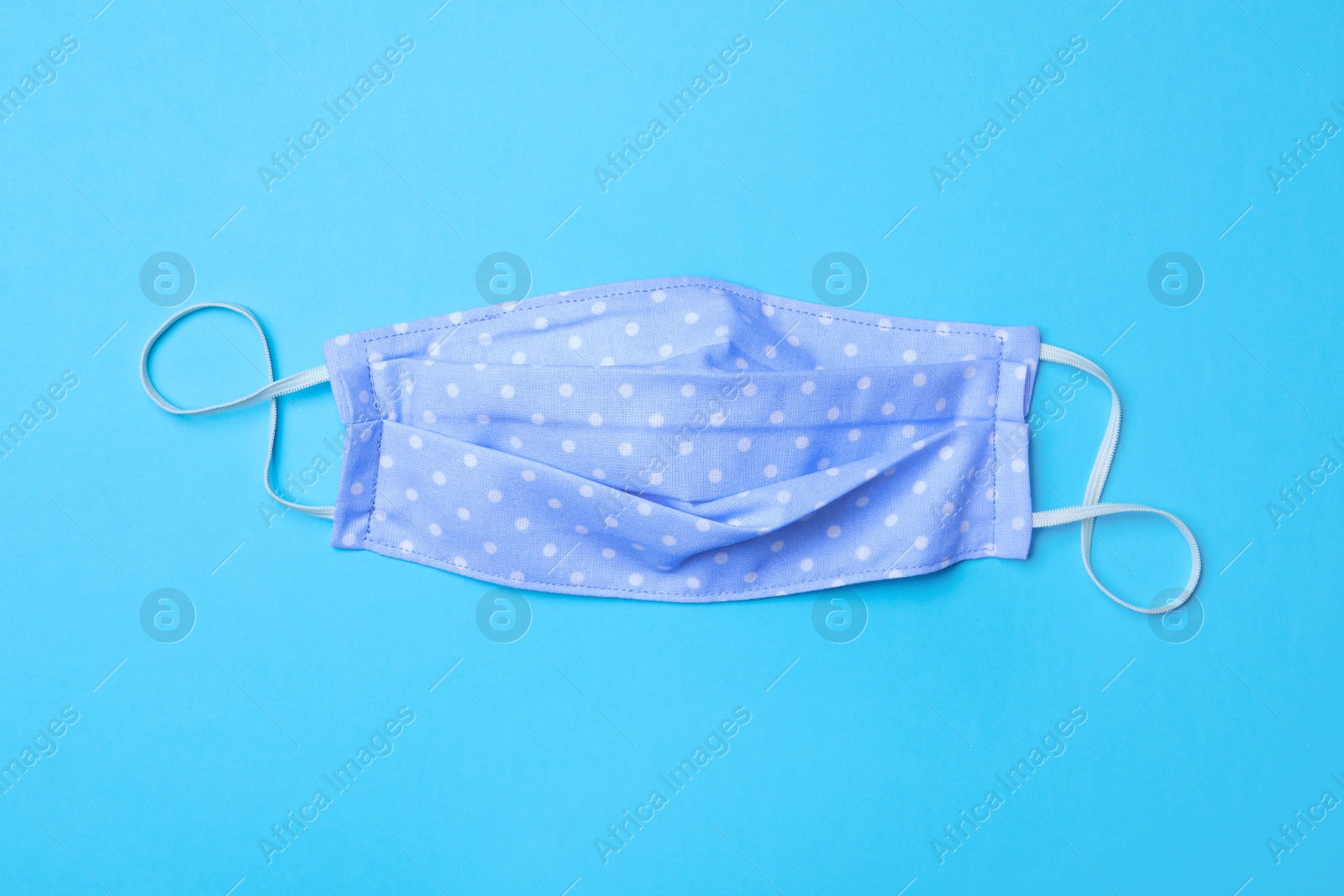 Photo of Homemade protective mask on light blue background, top view. Sewing idea