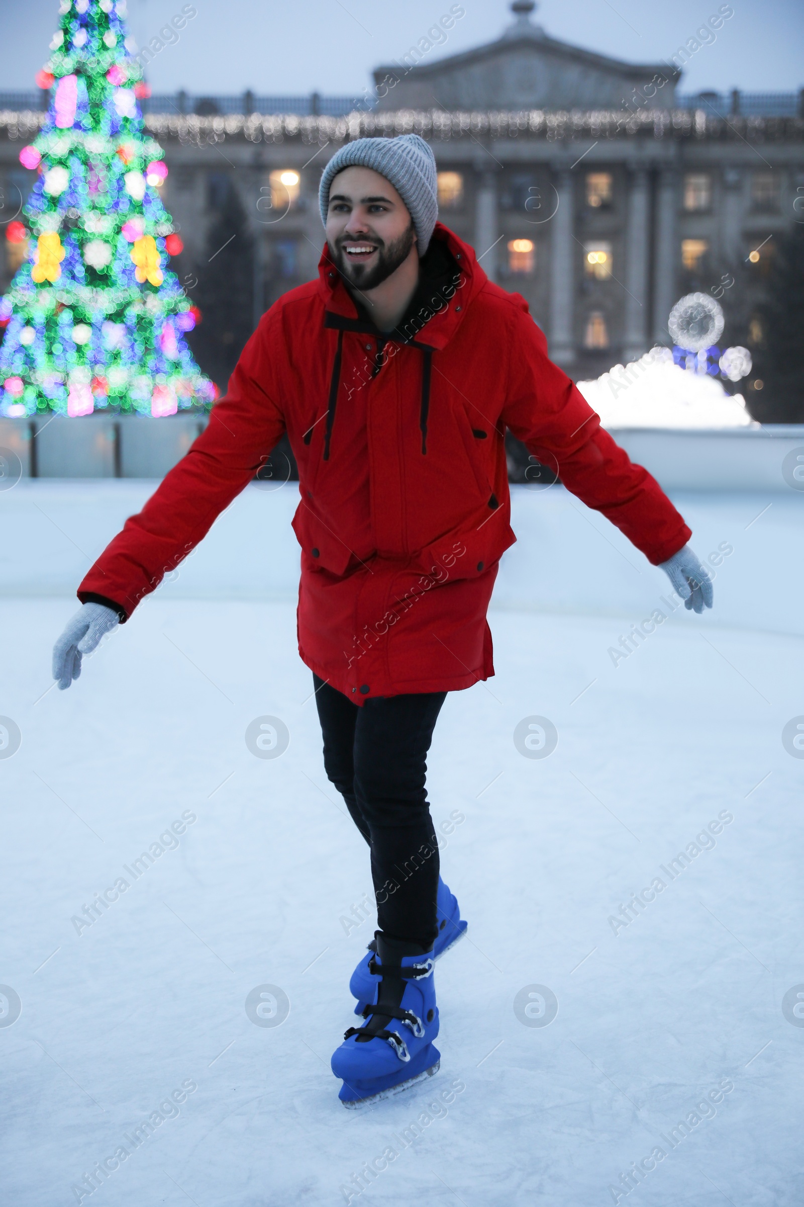 Image of Happy young man skating at outdoor ice rink