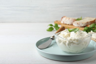 Photo of Tasty cream cheese with basil on white wooden table. Space for text