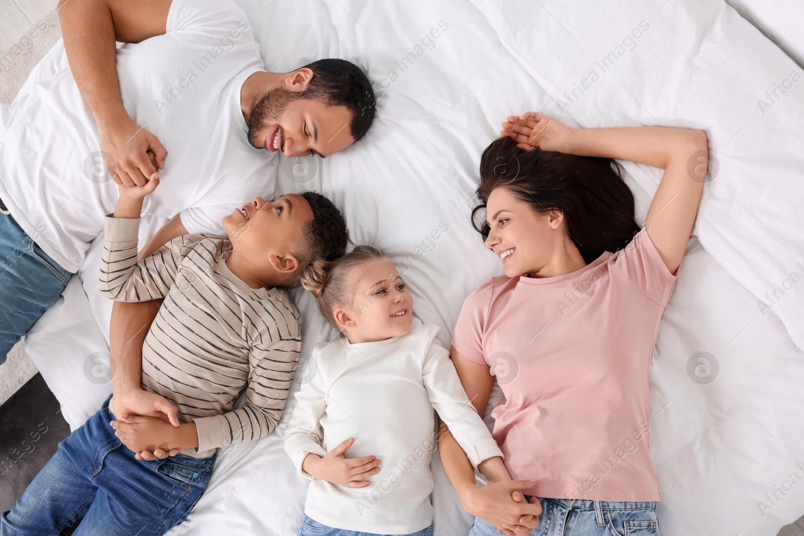 Photo of Happy international family lying on bed, top view