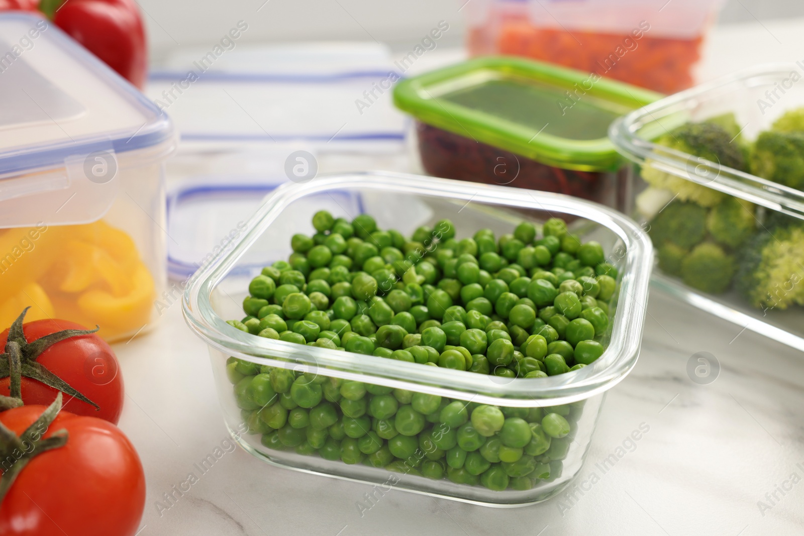 Photo of Containers with green peas and fresh products on white marble table, closeup. Food storage