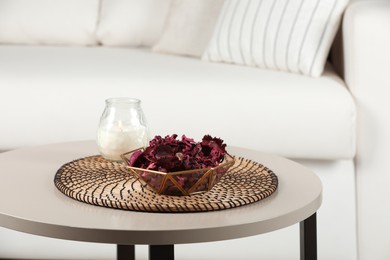 Photo of Aromatic potpourri of dried flowers in bowl and candle on white table indoors