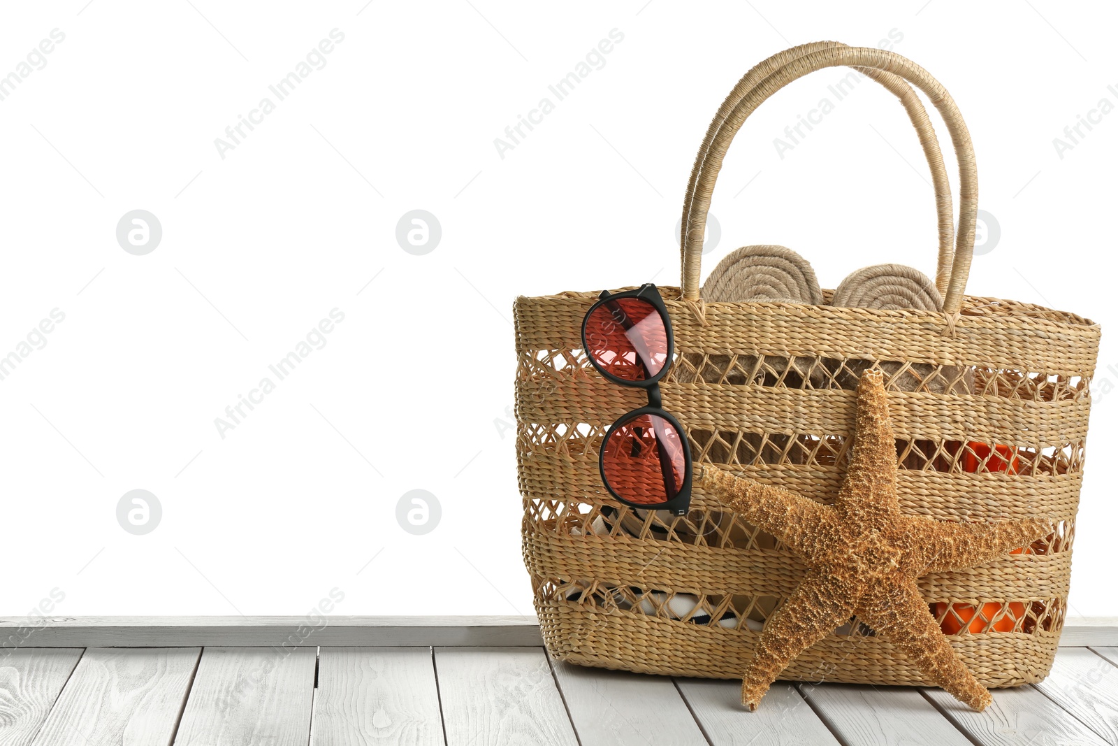 Photo of Stylish bag with beach accessories on white wooden table. Space for text