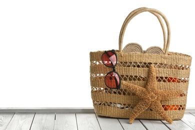 Photo of Stylish bag with beach accessories on white wooden table. Space for text