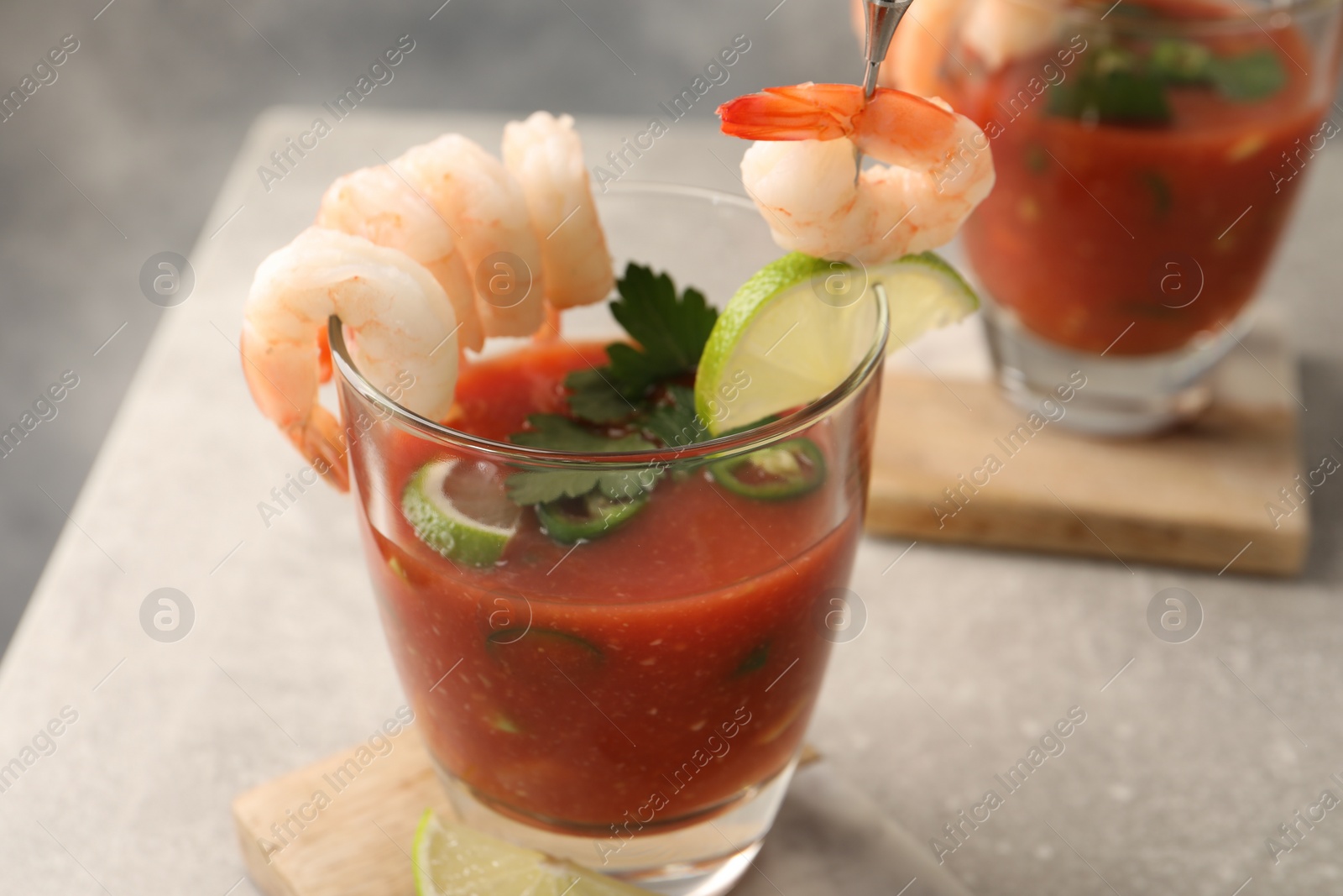 Photo of Tasty shrimp cocktail with sauce in glasses and lime on light grey table, closeup