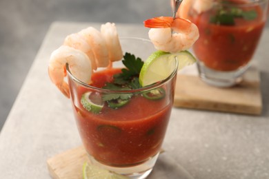 Photo of Tasty shrimp cocktail with sauce in glasses and lime on light grey table, closeup