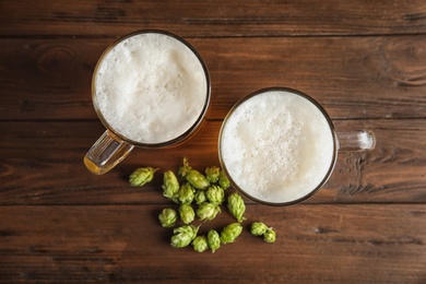 Photo of Flat lay composition with tasty beer and fresh green hops on wooden background
