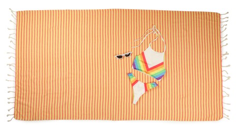 Striped beach towel with swimsuit and sunglasses on white background, top view