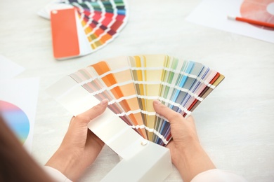 Woman with paint color palette samples at table, closeup
