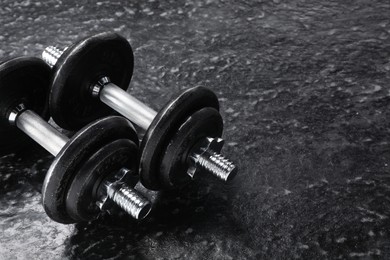 Two barbells on dark textured floor, closeup. Space for text