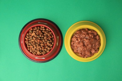 Dry and wet pet food in feeding bowls on green background, flat lay