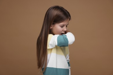 Sick girl coughing on brown background. Cold symptoms